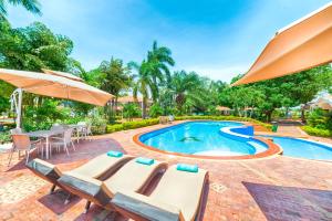 una piscina con tumbonas y sombrilla en Hotel Campestre La Potra, en Villavicencio