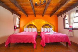 2 Betten in einem Zimmer mit orangefarbenen Wänden in der Unterkunft Hotel Jovel - Pago solo en efectivo in San Cristóbal de las Casas