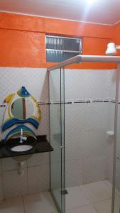 a bathroom with a glass shower with a sink at Pousada Casa Branca in Salinópolis