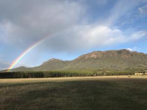 a rainbow over a field with mountains in the background at BIG4 Taggerty Holiday Park in Taggerty