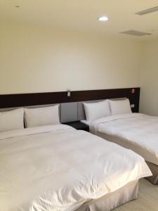 a hotel room with two beds and two nightstands at Big Bear Hotel in Kaohsiung