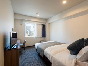 a hotel room with a bed and a flat screen tv at HOTEL MYSTAYS Sapporo Nakajima Park Annex in Sapporo