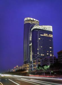 Un grand bâtiment est éclairé la nuit. dans l'établissement Sofitel Guangzhou Sunrich, à Canton