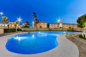 una piscina por la noche con edificios en el fondo en Hotel Gran Playa, en Santa Pola