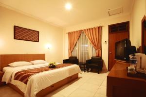 um quarto de hotel com uma cama e uma televisão em Syariah Arini Hotel em Surakarta