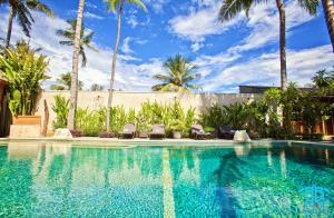 a swimming pool with two chairs and palm trees at Benthos Bali Dive Resort in Candidasa