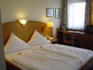 Schlafzimmer mit einem Bett mit weißer Bettwäsche und einem Schreibtisch in der Unterkunft Hohenzollern in Bad Neuenahr-Ahrweiler