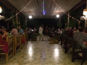 a crowd of people sitting in a restaurant with a dog laying on the floor at Starlight Beach Resort in Ko Phayam