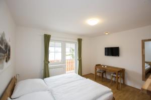 Schlafzimmer mit einem Bett, einem Fenster und einem Tisch in der Unterkunft Bierhotel Ranklleiten Almtal in Pettenbach