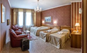 a hotel room with two beds and a chair at Hotel Sorriso in Lucera