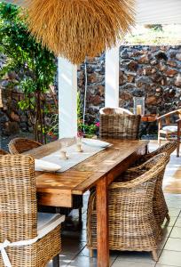 drewniany stół z rattanowymi krzesłami na patio w obiekcie Senteur Vanille w mieście Saint-Gilles les Bains