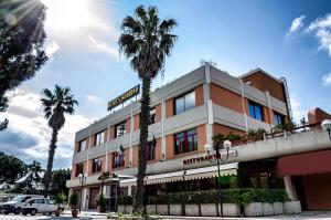 a building with palm trees in front of it at Hotel Sorriso in Lucera