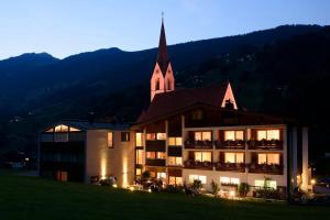 un grand bâtiment avec une église la nuit dans l'établissement Hotel Silbertal, à Silbertal