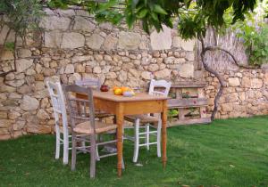 una mesa de madera con 4 sillas y una pared de piedra en Villa Vigles, en Vóroi