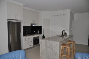 A kitchen or kitchenette at MODERN 3 BEDROOM APARTMENT IN TRADITIONAL QUEENSLANDER , PATIO, LEAFY YARD, POOL