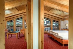 Schlafzimmer mit einem Bett, einem Tisch und Fenstern in der Unterkunft Hotel Dufour Chalet - Adults only in Zermatt