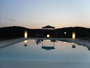 a man sitting next to a swimming pool at sunset at Agriturismo Podere Borgognano in Massa Marittima