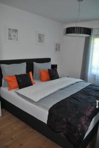 ein Schlafzimmer mit einem großen Bett mit orangefarbenen und grauen Kissen in der Unterkunft Ferienwohnung Krause in Oberammergau