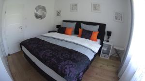 1 dormitorio con 1 cama grande con almohadas de color naranja y morado en Ferienwohnung Krause en Oberammergau