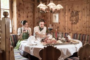 a man and woman sitting at a table with a tray of meat at Hotel Tauernblick - Thermenhotels Gastein in Bad Hofgastein
