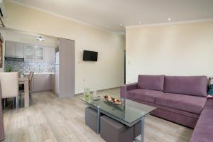 sala de estar con sofá púrpura y mesa en Studios Gagos en Astris