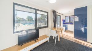 un salon avec une grande télévision et une table dans l'établissement Batavia Apartments, à Perth