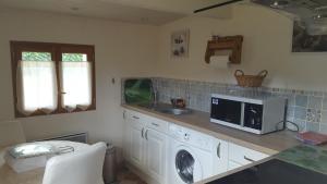 a kitchen with a sink and a washing machine at Gîte Ti-Case in Bussac-Forêt