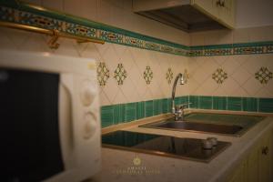 a kitchen with a sink and green and white tiles at Amalfi Cathedral Suite in Amalfi