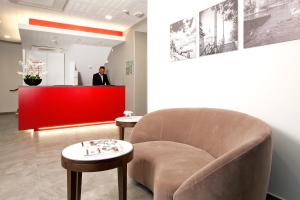 a man standing at a red counter with a chair in a room at Residhome Paris Rosa Parks in Paris