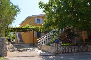 żółty dom z płotem przed nim w obiekcie Apartment MARA w mieście Šilo +5 zdjęć