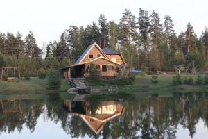 una cabina in riva a un lago con la sua riflessione nell'acqua di Viesu māja Forrest a Dzimtmisa