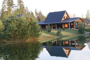 a log cabin with a reflection in the water at Viesu māja Forrest in Dzimtmisa