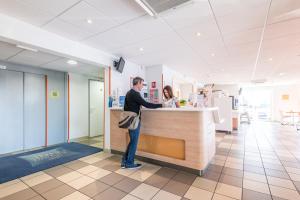 a man standing at a counter in a store at ibis budget Amberieu en Bugey/Chateau Gaillard A42 in Château-Gaillard