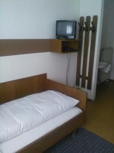 a bedroom with a bed with a tv on the wall at Gasthof Schatzl in Grieskirchen