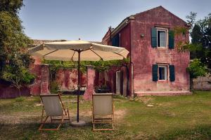 two chairs and an umbrella in front of a house at Roumanades Estate in Roumanádes