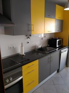 a kitchen with yellow cabinets and a stove top oven at casa da teresa in Olhão