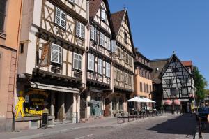 a city street with tall buildings with tables and chairs at Gîte Grand'Rue "Climatisé" in Colmar
