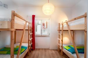 a room with three bunk beds and a window at Nazaré Hostel - Rooms & Dorms in Nazaré