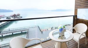 a balcony with a table and chairs and the water at Shang Shan Ting Chao Hotel in Yuchi
