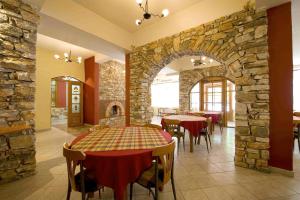 a restaurant with tables and chairs and a stone wall at Lydia Hotel in Krinídhes