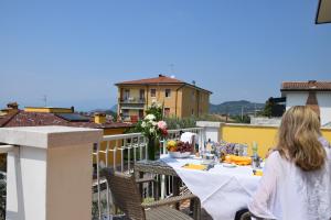 a woman sitting at a table on a balcony at Villa Mimosa in Bardolino