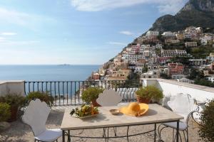 een tafel en stoelen op een balkon met uitzicht op de stad bij Villa Rosa in Positano