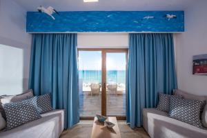 - un salon avec des rideaux bleus et une vue sur l'océan dans l'établissement Yianna Caravel "by Checkin", à Amoudara