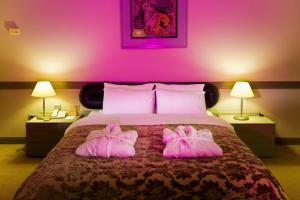 a bedroom with a bed with two pink pillows at Fantasia Deluxe Hotel in Kuşadası