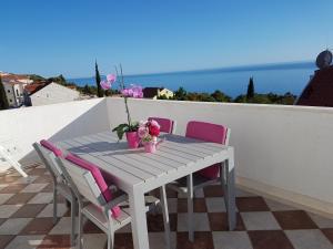 a table with pink chairs and flowers on a balcony at Apartments Antonio in Cavtat