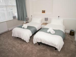 a hotel room with two beds with white sheets at Longstone House Bed & Breakfast in Seahouses