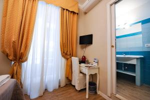 una camera da letto con scrivania, lavandino e finestra di Onda Marina Rooms a Cagliari