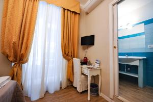 sypialnia z biurkiem, umywalką i oknem w obiekcie Onda Marina Rooms w Cagliari
