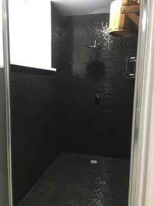 a black bathroom with a shower with black tiles at Alkor Hotel in Volgograd