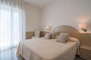 a white bedroom with a large bed with pillows at Hotel Dolomiti in Caorle